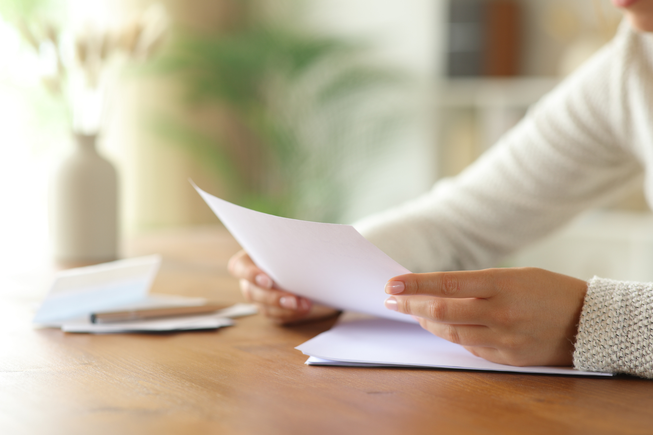 Close up of a woman hand reading card on wooden table in a house interior