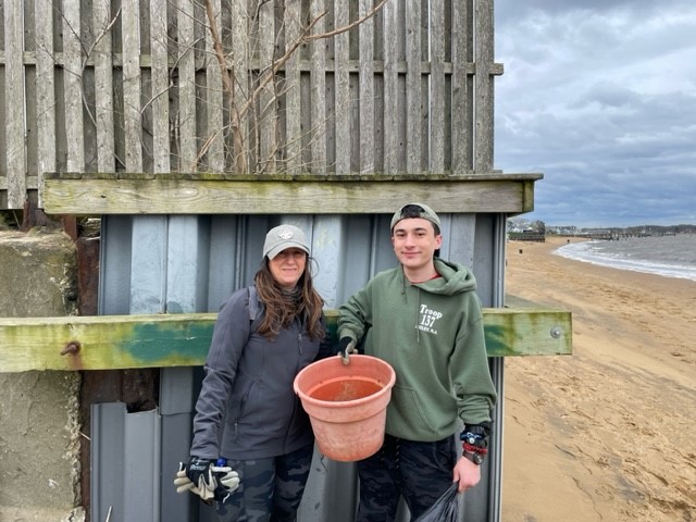 A person and person standing next to a metal shed

Description automatically generated